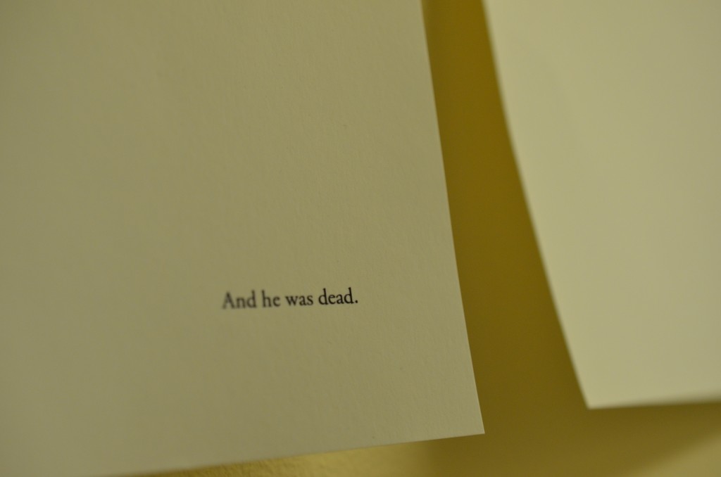 two sheets of a4 paper hang are pinned to a wall. Each sheet has a single line of typewritten text on it. In the bottom right hand corner of the left sheet, is written the line 'And he was dead.' full stop. In the top left hand corner of the right sheet, is written the line 'Everybody dies,' comma.